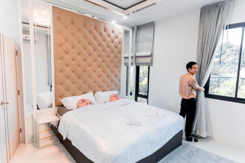 a man standing in a bedroom with a large bed at Ying Yang House Sawankhalok in Sawankhalok