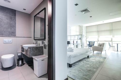 a bathroom with a sink and a bed in a room at Nasma Luxury Stays - White Haven Studio With Charming Cityscape Views in Dubai