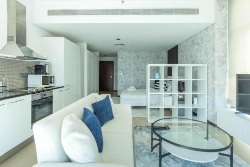 a living room with a white couch and a glass table at Nasma Luxury Stays - White Haven Studio With Charming Cityscape Views in Dubai