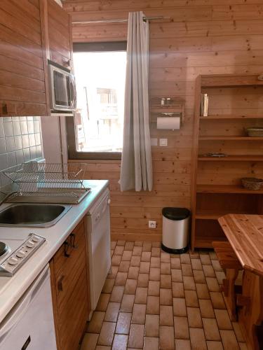 - une cuisine avec des murs en bois, un évier et une fenêtre dans l'établissement Le cocon Risoul, à Risoul