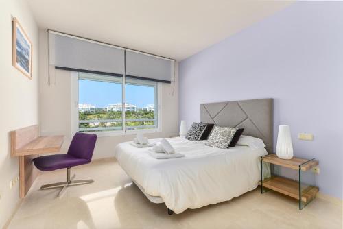ein Schlafzimmer mit einem großen Bett und einem lila Stuhl in der Unterkunft Alcazaba Lagoon 2425 Luxury private beach in Estepona