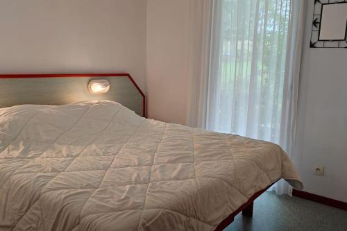 ein Schlafzimmer mit einem Bett mit einer weißen Bettdecke und einem Fenster in der Unterkunft Adour Piscine Vue Montagnes in Souraïde