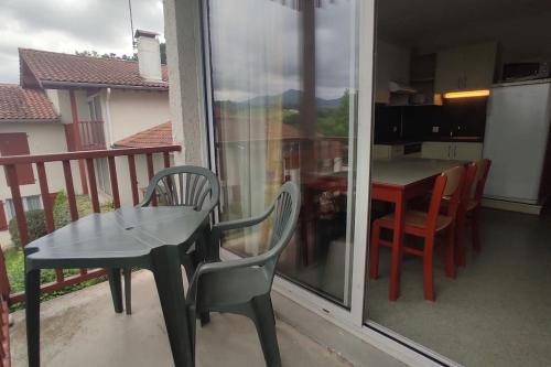einen Balkon mit einem Tisch und Stühlen sowie eine Küche in der Unterkunft Adour Piscine Vue Montagnes in Souraïde