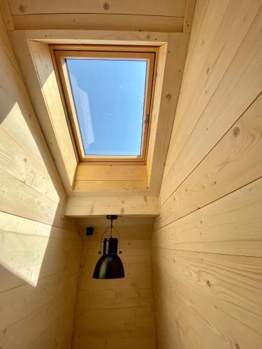a window in the ceiling of a wooden cabin with a light at Apartament Widoknastok in Korbielów