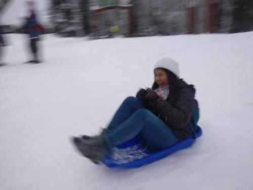 a woman sitting on a sled in the snow at Backyard Cabin With Veranda By Kemi River In Keminmaa in Kemi