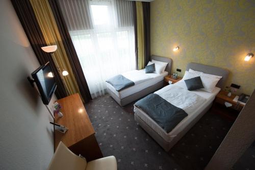 a hotel room with two beds and a television at Hotel Alina in Wiesbaden