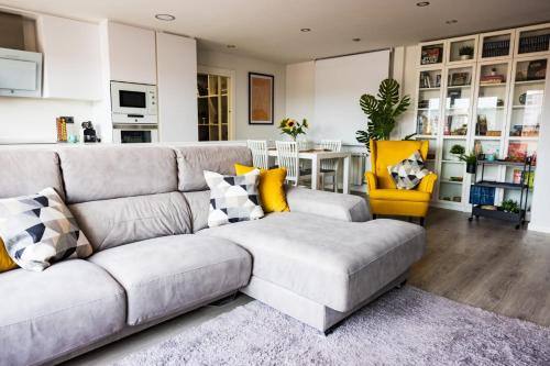 a living room with a gray couch and a yellow chair at Lujoso ático entre 2 playas con garaje in Gijón