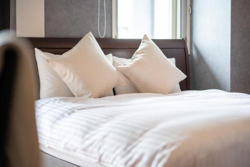 a bed with white sheets and pillows in front of a window at Residence Hotel Hakata 8 in Fukuoka