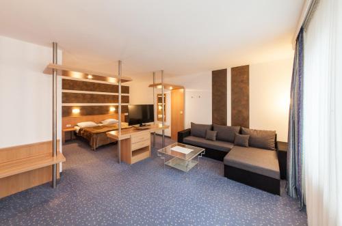uma sala de estar com um sofá e uma cama em Hotel am Seegraben em Cottbus