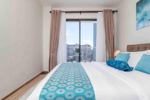 Un dormitorio con una gran cama blanca con una gran ventana. en A cozy and elegant apartment, en Nairobi