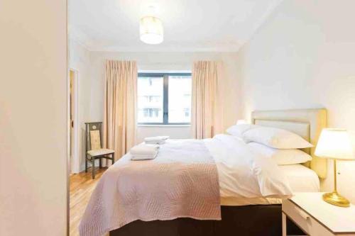 a white bedroom with a large bed and a mirror at Luxury Two Bedroom Apt in Dublin in Dublin