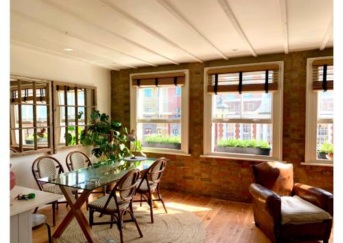 a dining room with a table and chairs and windows at Your Private Hoxton Apartment Sleeps 3 London Zone 1 in London