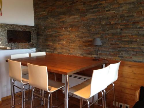 a dining room table with white chairs and a brick wall at Appartement charme CHAMROUSSE in Chamrousse