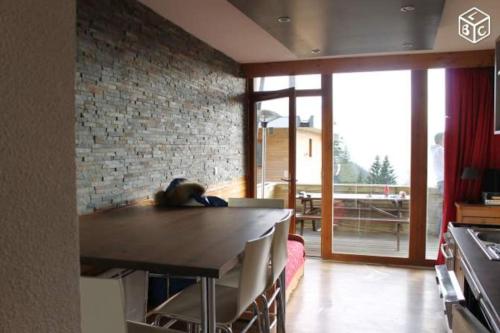 a kitchen with a table and a brick wall at Appartement charme CHAMROUSSE in Chamrousse