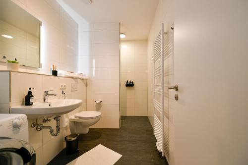 La salle de bains blanche est pourvue d'un lavabo et de toilettes. dans l'établissement Ferienwohnungen am Theater - modern, zentral und ruhig mit Küche, Waschtrockner, Netflix, Wlan und Parkplatz- 2 Zimmer, 52 qm, à Cottbus