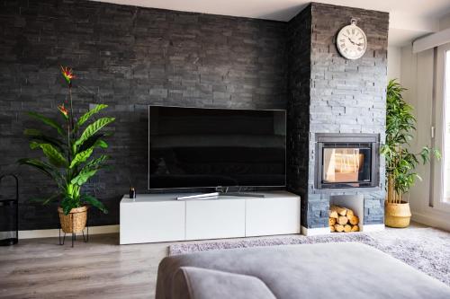 a living room with a tv and a brick wall at Lujoso ático entre 2 playas con garaje in Gijón