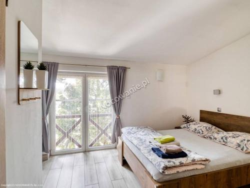 um quarto com uma cama e uma grande janela em Pokoje przy Bulwarach em Uniejow