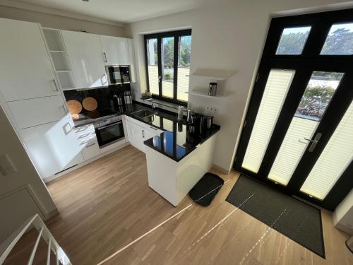 a kitchen with white cabinets and a black counter top at Ferienwohnung "Julie" - Haus Alando in Prora