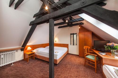 a bedroom with a bed and a desk with a computer at Novum Hotel Ahl Meerkatzen Köln Altstadt in Cologne