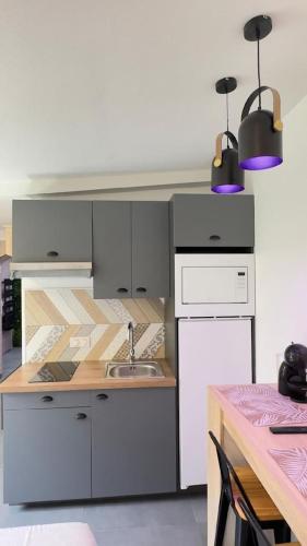 - une cuisine avec des placards blancs, un évier et deux lumières dans l'établissement La Suite Sun Set, à Tremblay-en-France