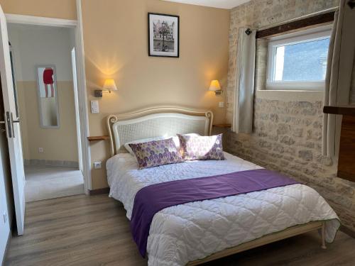 Un dormitorio con una cama con sábanas moradas y una ventana en Gîte UTAH - 4 personnes - Plages du débarquement, en Formigny