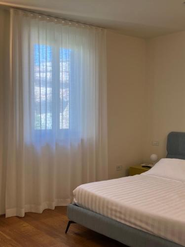 1 dormitorio con 1 cama y una ventana con cortinas blancas en Urbino Apartment - Urban Retreat, en Urbino