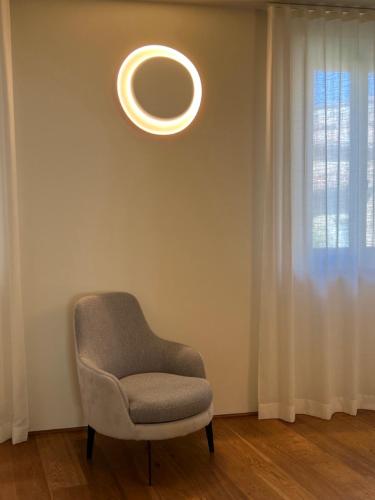 una silla sentada en una habitación con una luz circular en Urbino Apartment - Urban Retreat, en Urbino