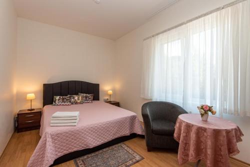 a bedroom with a bed and a chair and a table at Guest House Pasaulio Krastas in Palanga