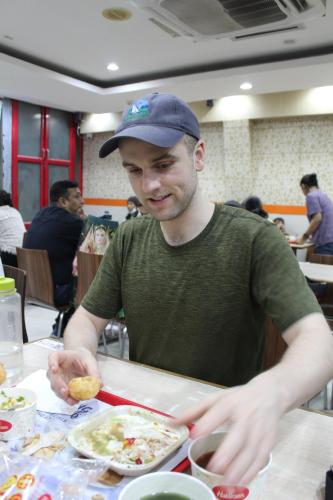 a man sitting at a table with a plate of food at Friends Hostel by Backpackers Heaven- New Delhi Railway Station - Paharganj in New Delhi
