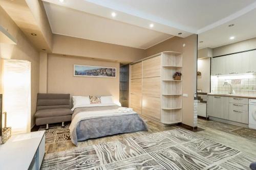 a bedroom with a bed and a couch and a kitchen at Арбат in Almaty