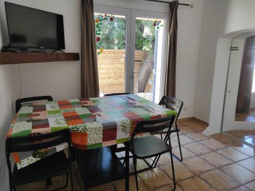 une salle à manger avec une table, des chaises et une télévision dans l'établissement Maisonnette 1 chambre Climatisation Calme Jardin BBQ Plages, à La Seyne-sur-Mer
