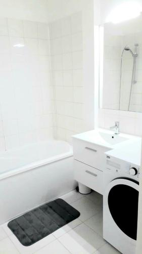La salle de bains blanche est pourvue d'un lavabo et d'un lave-linge. dans l'établissement Modern 1 bed flat - Near Arc de Triomphe & Champs Elysees, à Paris