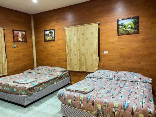 two beds in a room with wooden walls at Loongmun Beach in Cha Am