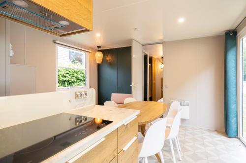 eine Küche mit einem Holztisch und weißen Stühlen in der Unterkunft ArdenParks Petite Suisse in Dochamps