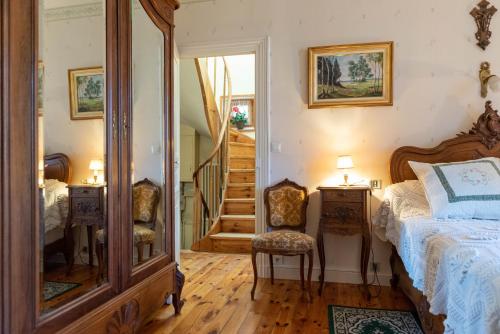 - une chambre avec un lit, un miroir et un escalier dans l'établissement La Maison de Mireille, au Puy-en-Velay