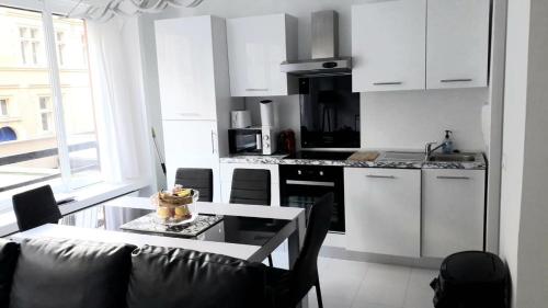 - une cuisine avec des placards blancs et une table avec un gâteau dans l'établissement Modern 1 bed flat - Near Arc de Triomphe & Champs Elysees, à Paris