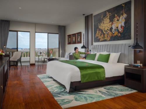 a man in a hotel room with a large bed at Borei Angkor Resort & Spa in Siem Reap