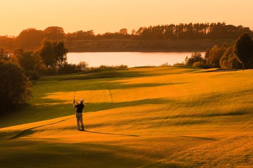 a man holding a golf club on a golf course at Tulfarris Hotel and Golf Resort in Blessington