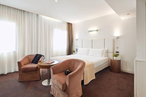 a hotel room with a bed and two chairs at Hotel Plaza in Mestre