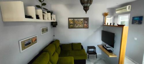 sala de estar con sofá verde y TV en Coqueto apartamento en La Barrosa de un dormitorio, en Chiclana de la Frontera