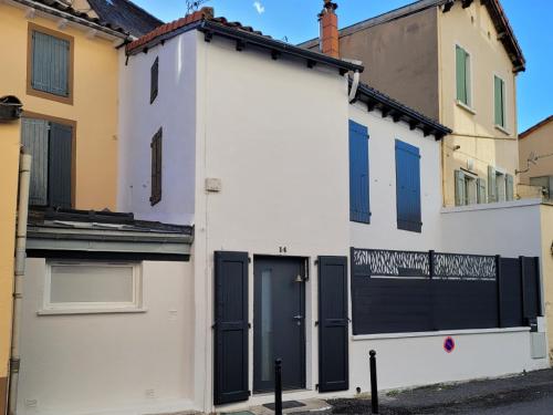 - un bâtiment blanc avec des portes et des fenêtres bleues dans l'établissement Maison de ville - Quai Sully, à Millau
