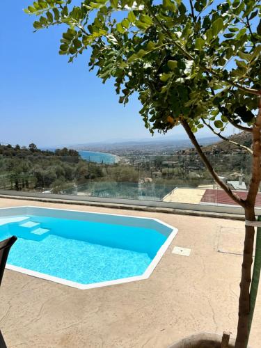 a swimming pool with a tree in the foreground at CRETelia House in Palaiokastro