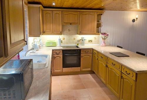 a kitchen with wooden cabinets and a sink at Hilltop Cottage/ Penrhiw in Maentwrog