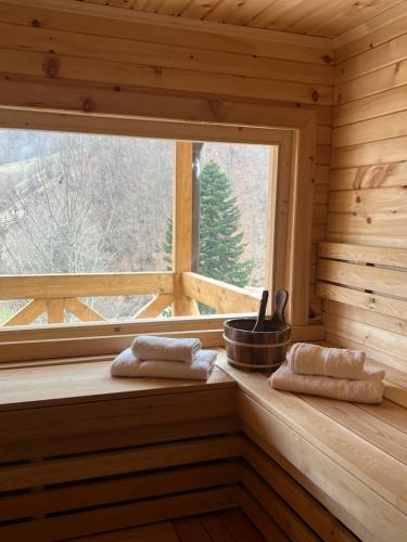 a window in a wooden cabin with towels on a bench at Planinska kuca Grujic in Kolašin