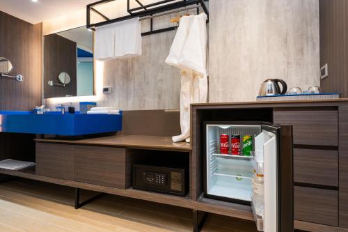 a kitchen with an open refrigerator with drinks in it at Maitria Hotel Rama 9 Bangkok - A Chatrium Collection in Bangkok