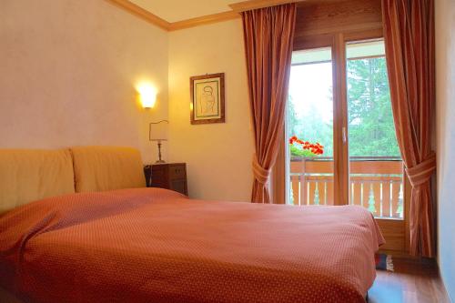 Schlafzimmer mit einem Bett und einem Fenster mit einem Balkon in der Unterkunft Charming 3 bedroom on Jack Nicklaus golf course - Estoril in Crans-Montana