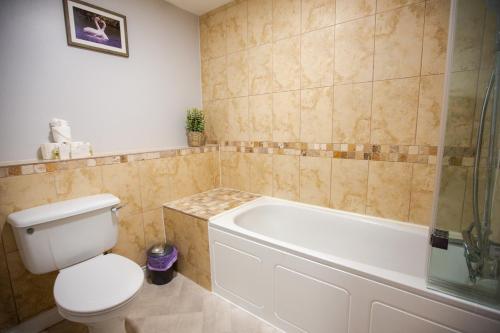 a bathroom with a toilet and a bath tub at Woodfalls Inn in Redlynch