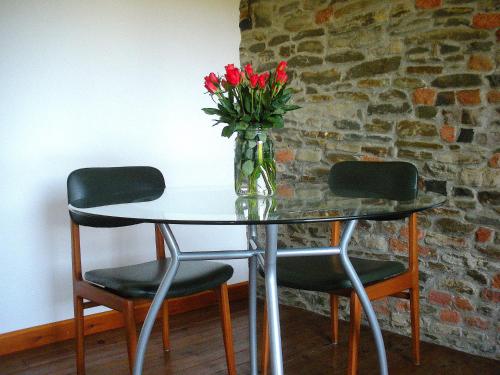 a glass table with two chairs and a vase of flowers at AMAZING LANGHE AND MONFERRATO | House with garden in Calamandrana