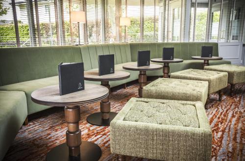 a waiting room with tables and chairs and windows at Mercure Bristol North The Grange Hotel in Bristol