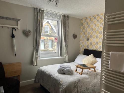 1 dormitorio con 1 cama con toallas en Cambridge House room only accommodation for Adults, en Windermere